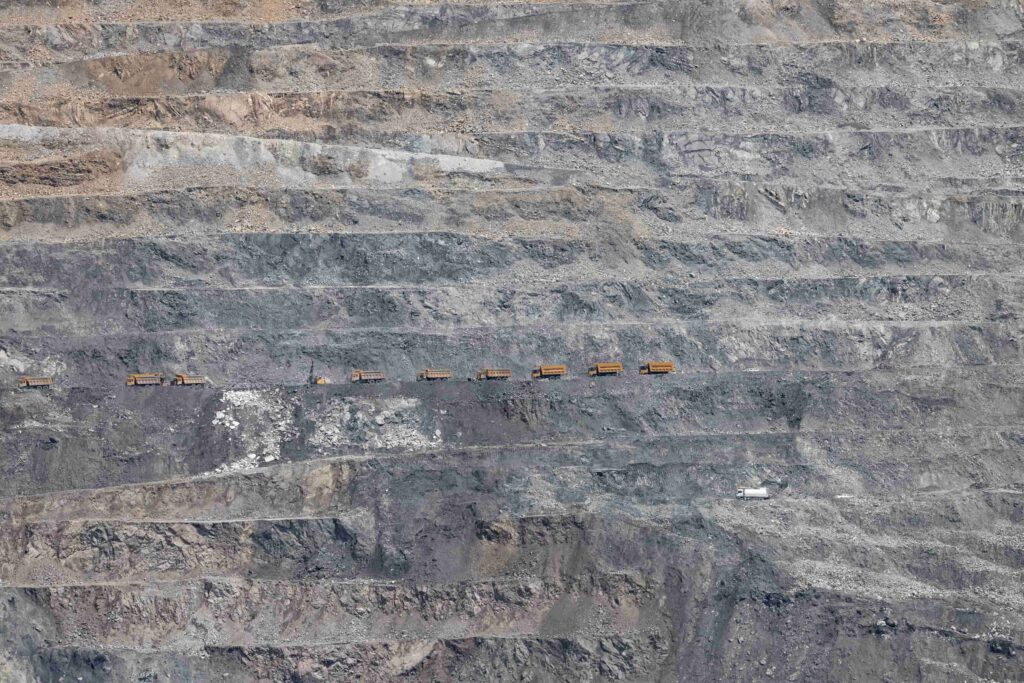 File de camions jaunes sur les gradins d’une mine à ciel ouvert