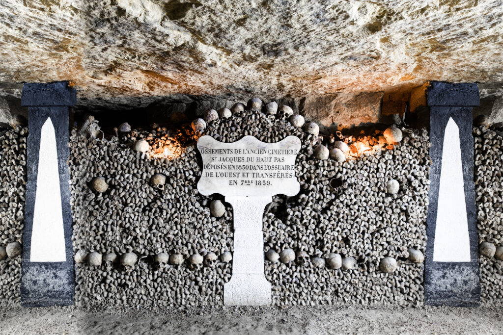 Mur d'ossements et de crânes de l'ossuaire, cartouche rappelant leur transfert en 1859